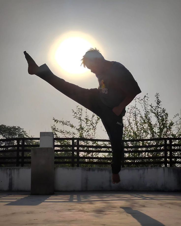 a man doing a kickbox pose in front of the sun