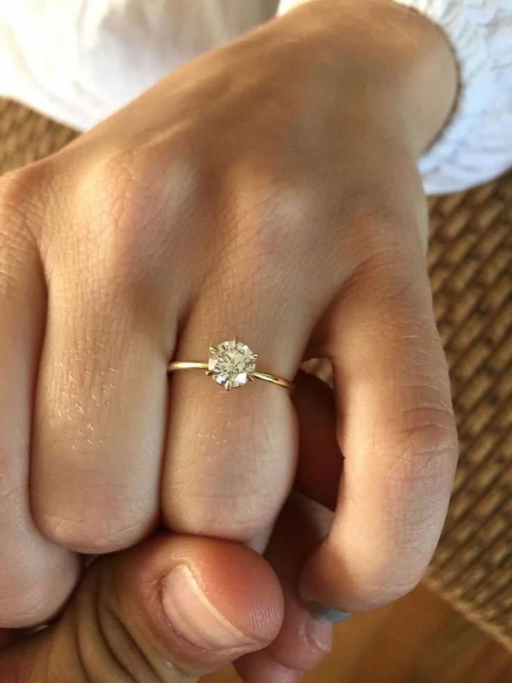 a close up of a person's hand with a diamond ring on their finger