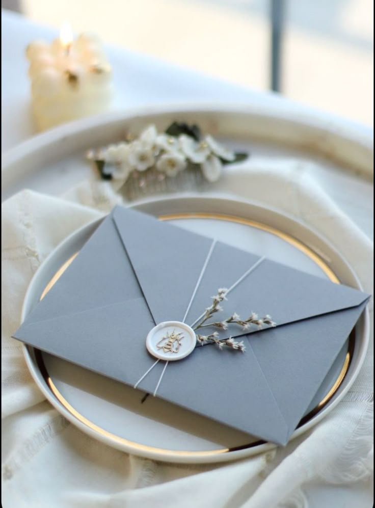 an envelope is sitting on top of a plate with some flowers in front of it