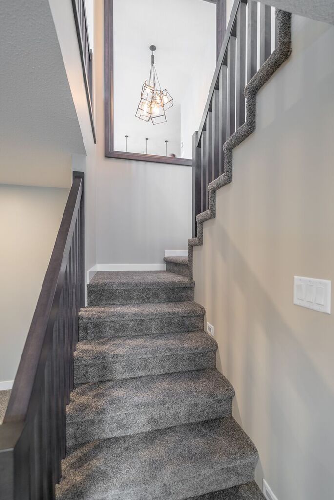 a staircase with carpeted steps leading up to a light fixture on the far wall