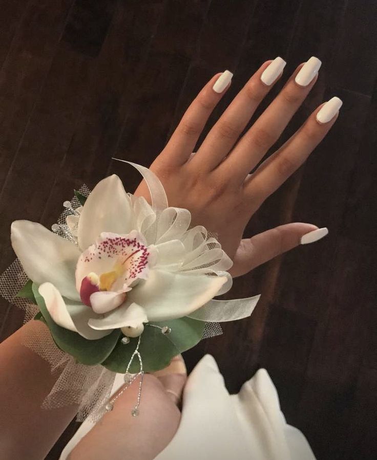 a woman's hand with white manies holding a flower