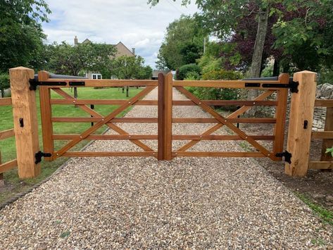 a wooden gate in the middle of a gravel driveway