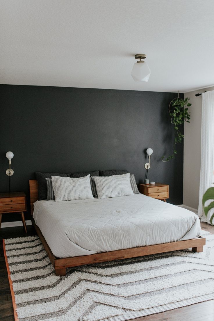 a bedroom with a bed, nightstands and rug on the floor in front of a window