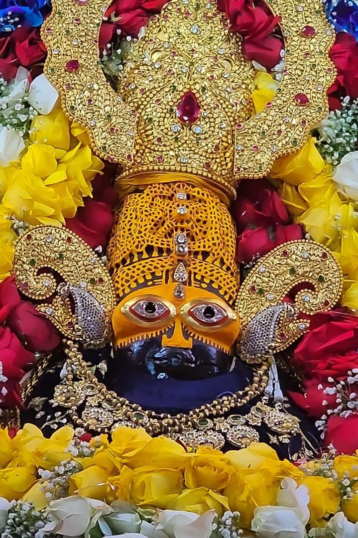 an elaborately decorated statue with flowers around it and a gold mask on the face