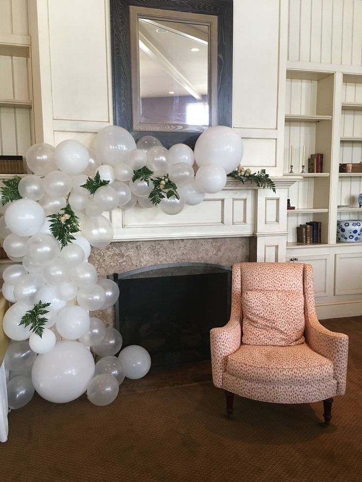 a living room filled with balloons and a chair next to a fire place in front of a fireplace