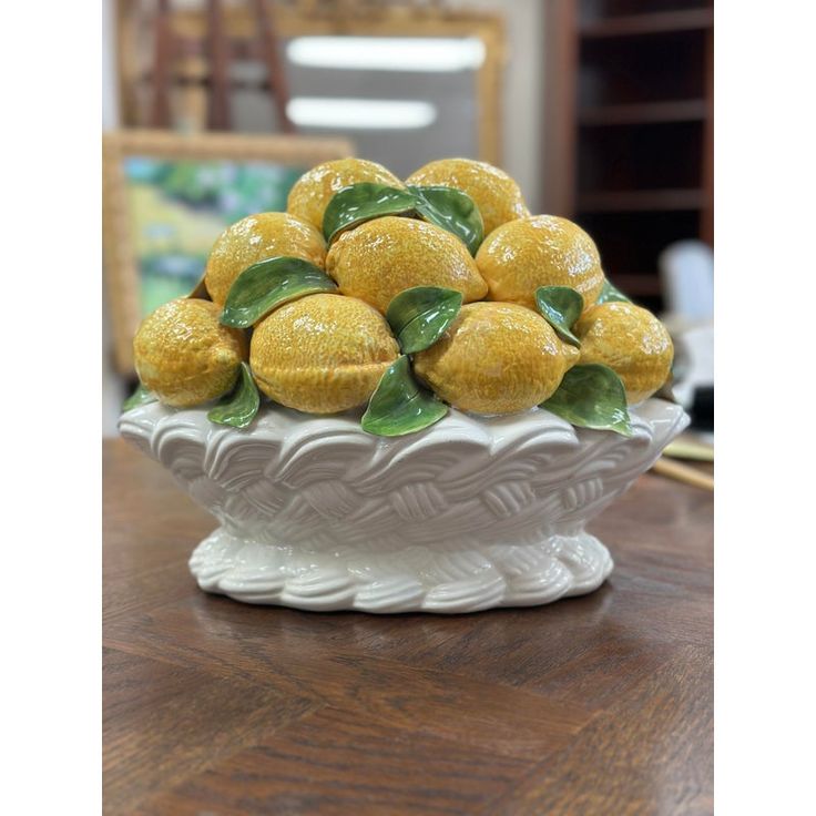 a white bowl filled with lemons on top of a wooden table