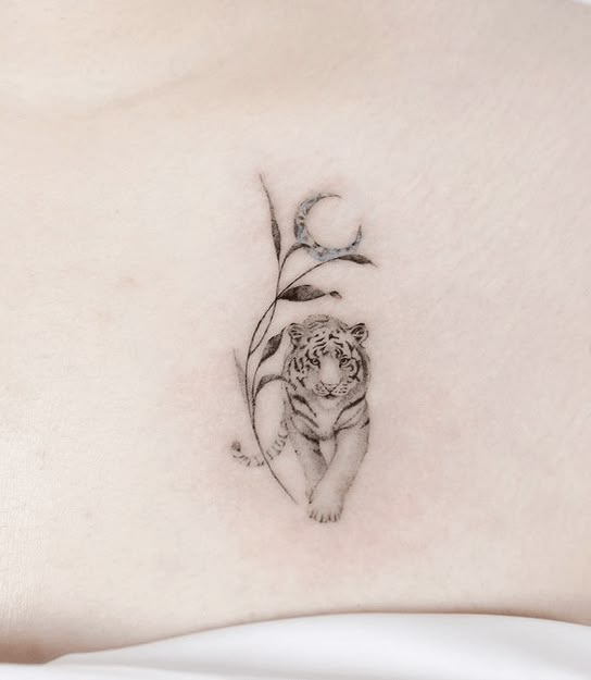 a small tiger tattoo on the back of a woman's stomach, with leaves