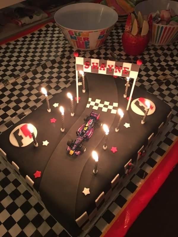 a birthday cake that is shaped like a race car with lit candles on the top