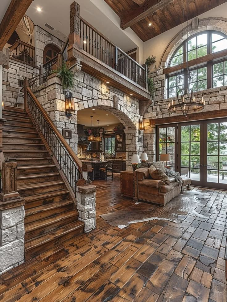 a large living room with wood floors and stone walls, along with an open staircase leading to the second floor