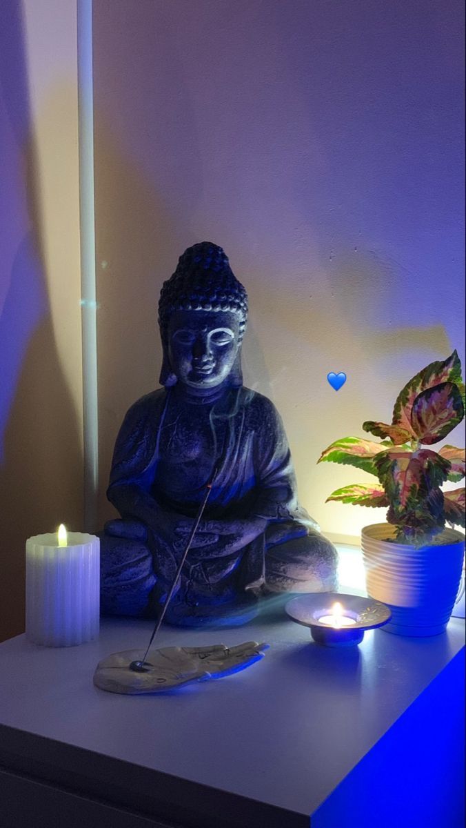 a buddha statue sitting on top of a table next to a lit candle