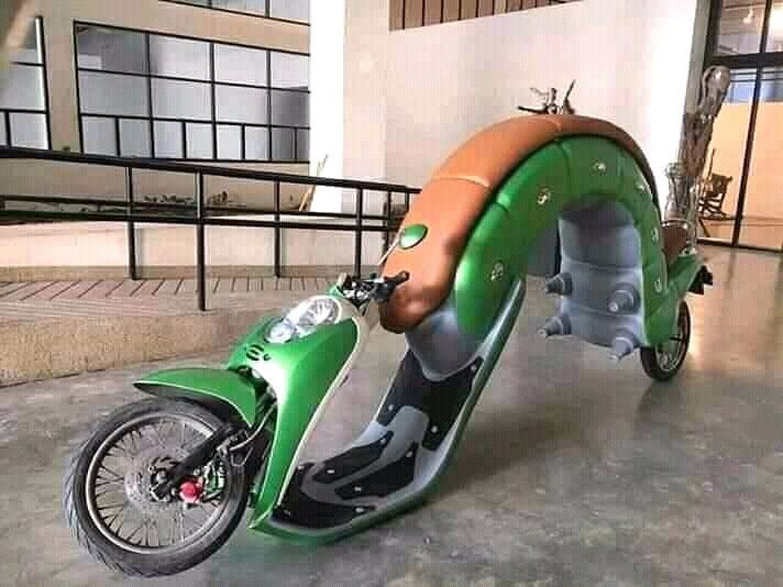 a green scooter with a hot dog on it's back tire is parked in front of a building