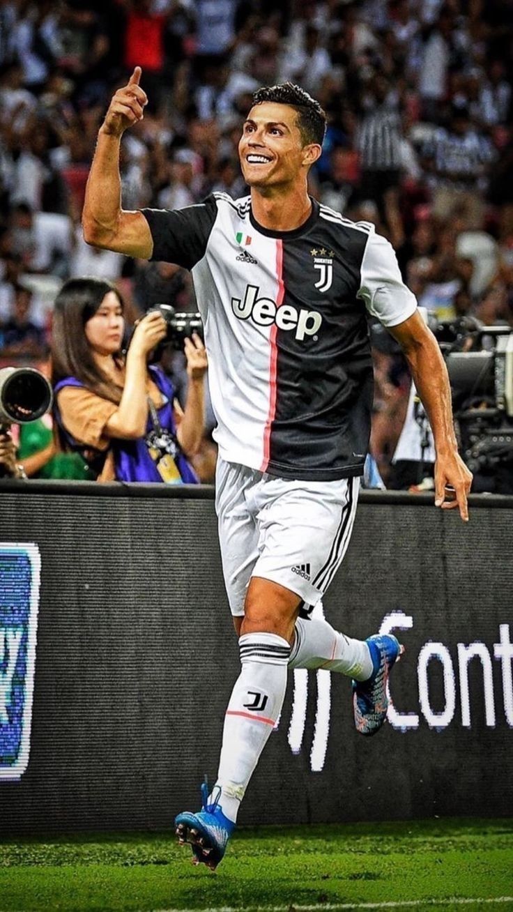 a soccer player is running on the field with his arms in the air as he celebrates