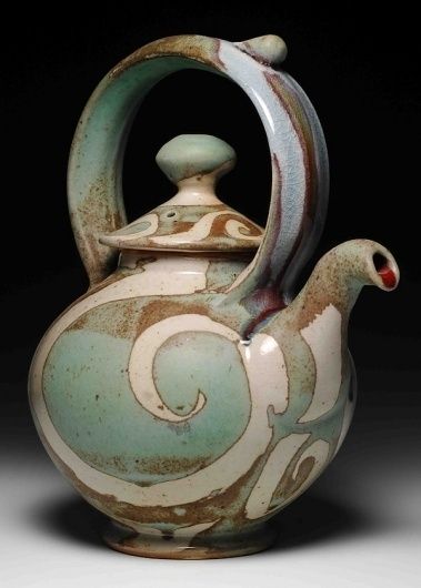 a ceramic teapot with a bird design on the front and sides, sitting on a black background