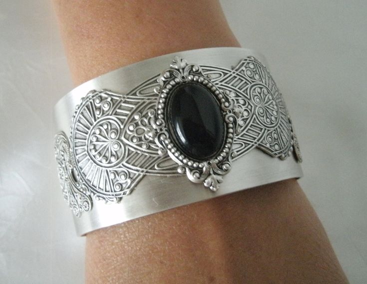 This beautiful silver plated cuff bracelet has a black onyx stone set on silver plated embellishments and silver plated gothic wings on the sides. Adjustable. Gothic Metal Jewelry With Filigree, Gothic Antique Silver Jewelry With Intricate Design, Gothic Filigree Metal Jewelry, Gothic Sterling Silver Jewelry With Intricate Design, Antique Silver Gothic Jewelry With Filigree, Antique Silver Gothic Filigree Jewelry, Gothic Antique Silver Filigree Jewelry, Gothic Sterling Silver Filigree Jewelry, Gothic Nickel-free Wedding Jewelry