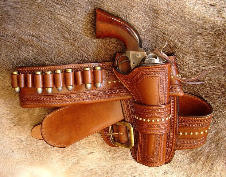 a pair of leather holsters sitting on top of a furry animal skin covered floor