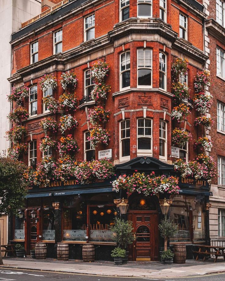 an old brick building with flowers growing on it's windows and balconies