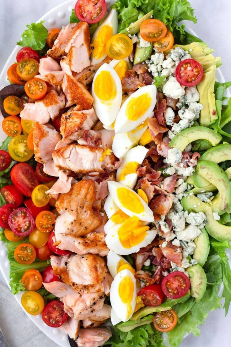 a salad with hard boiled eggs, tomatoes, avocado and lettuce