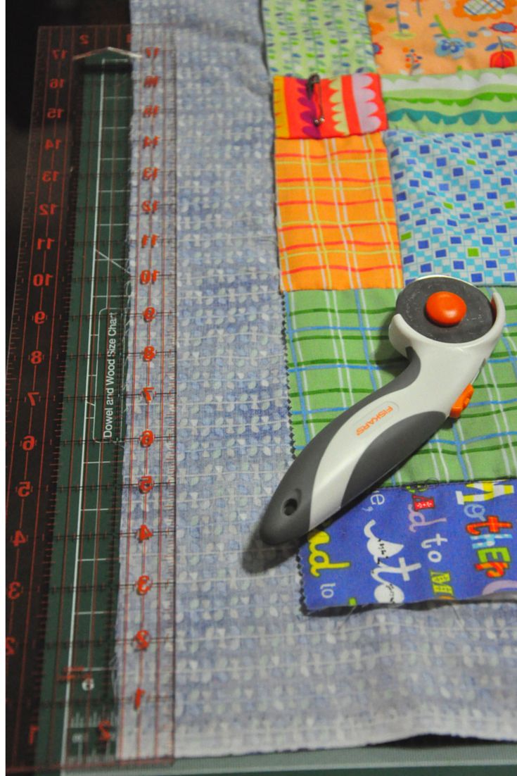 a pair of scissors sitting on top of a piece of fabric next to a ruler