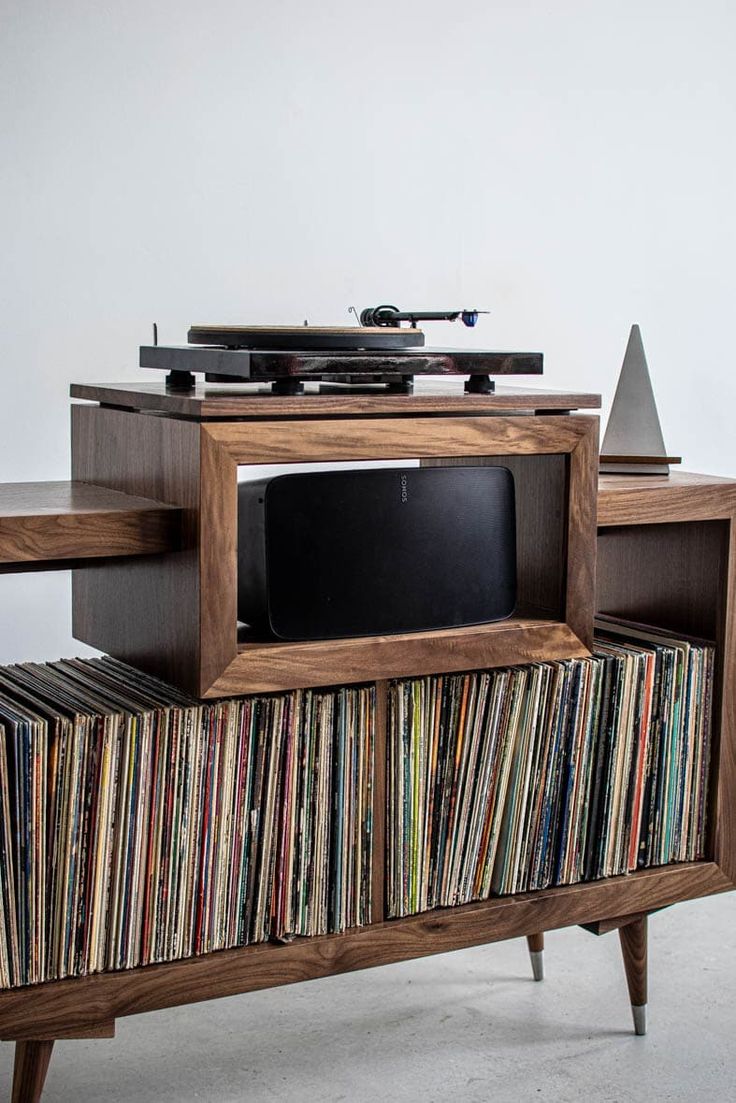 an entertainment center with record players and records on it's sides, in front of a white wall