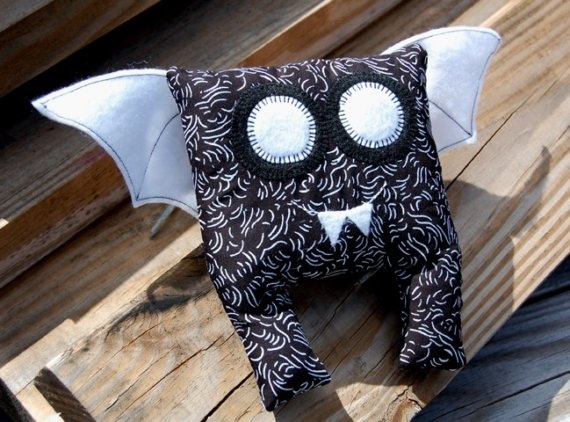 a bat stuffed animal sitting on top of a wooden bench