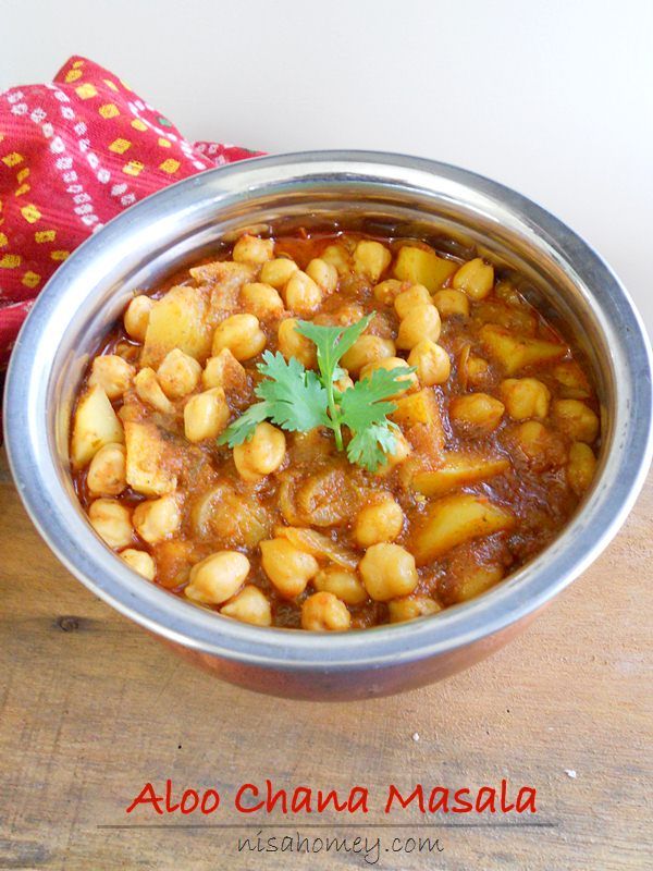 a metal bowl filled with chickpeas and garbanzo on top of a wooden table