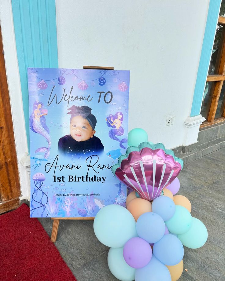 a welcome sign and balloons in front of a door with a mermaid theme on it