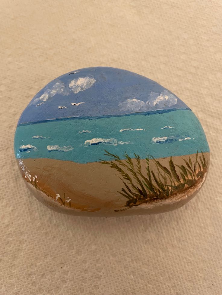 a painted rock sitting on top of a sandy beach