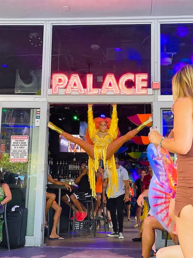 two women are dancing in front of a palace store with neon lights on the windows