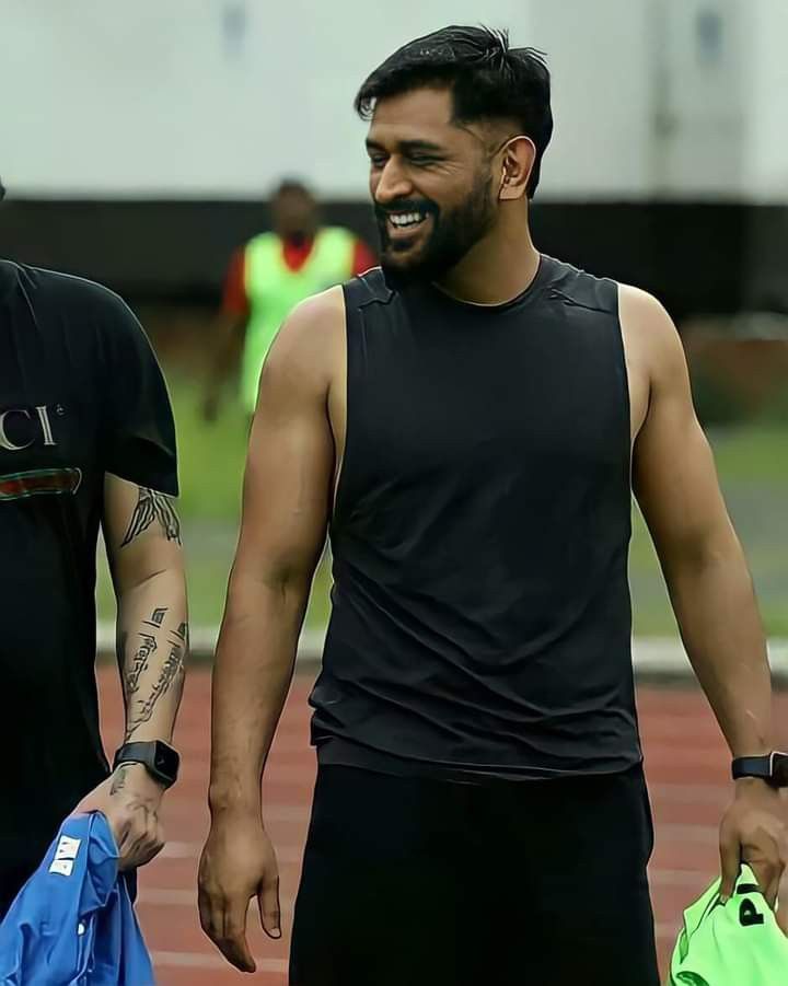 two men walking on a track with one holding a blue bag and the other wearing a black shirt