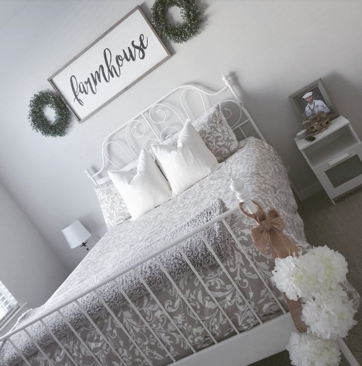 a white bed sitting in a bedroom next to a wall with wreaths on it