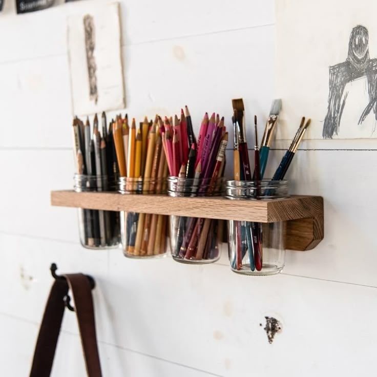 the wall is filled with many different colored pencils and paintbrushes in mason jars