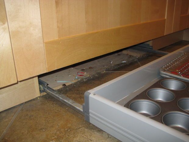 an open drawer in a kitchen filled with muffin tins