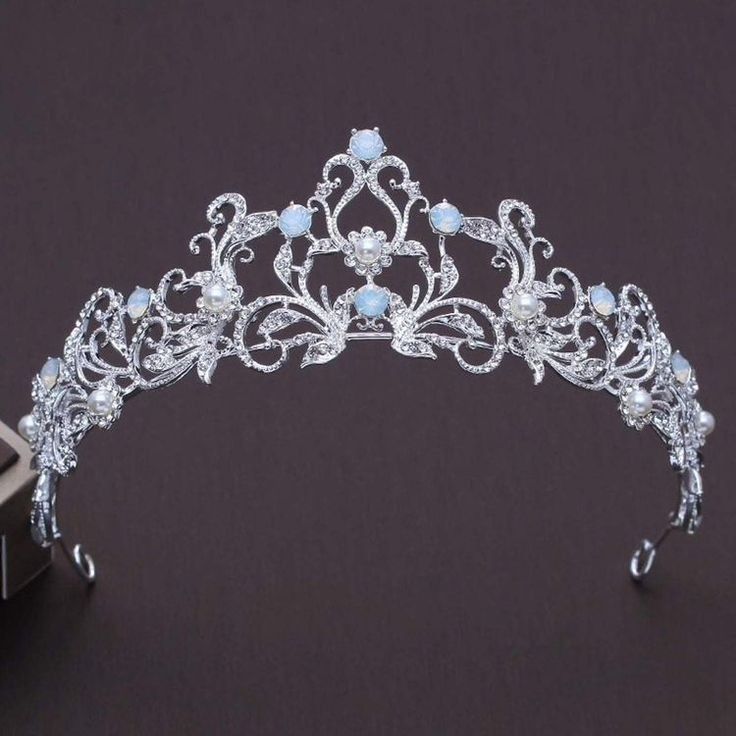 a tiara is shown on a black surface next to a small box with an object in it