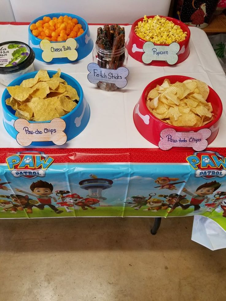 a table topped with bowls filled with chips and veggies on top of it