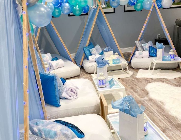 a room filled with lots of blue and white balloons on top of wooden poles next to couches