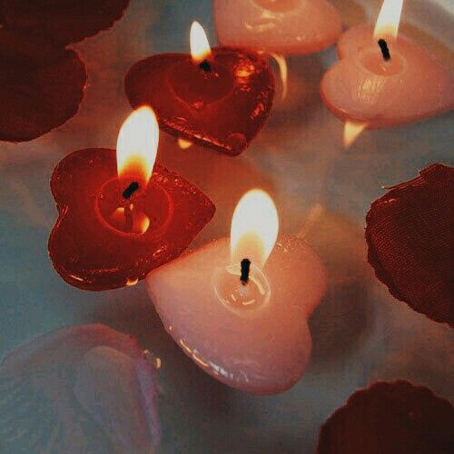 several lit candles with hearts on them floating in water and surrounded by other small ones