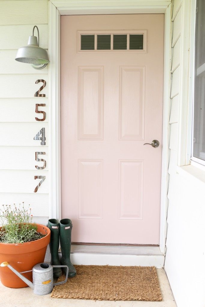 a pink front door with two flower pots next to it