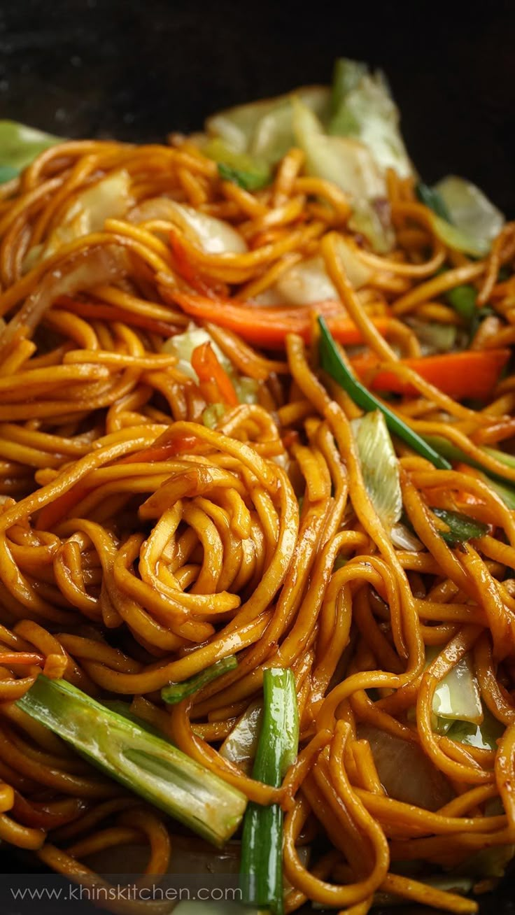 noodles and vegetables are being cooked in a wok