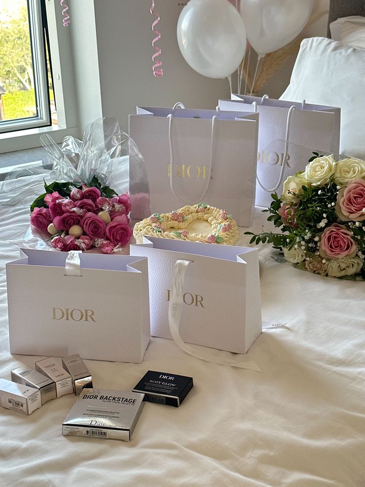 three bags on a bed with flowers, books and cake in front of the window