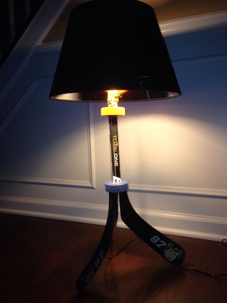 a lamp that is on top of a wooden floor with a black shade over it