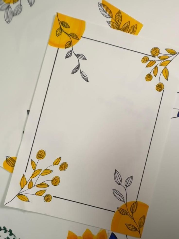 some yellow flowers and leaves are on white paper with black lines around the edges,