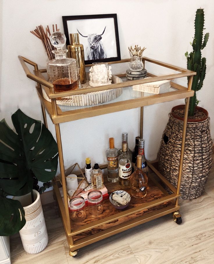 a bar cart filled with liquor bottles and other items next to a potted plant