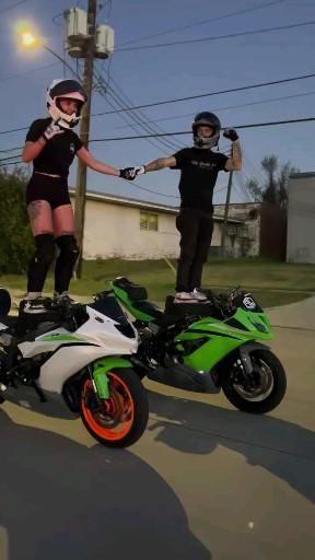 two people standing on top of motorcycles in the middle of the street with their hands up