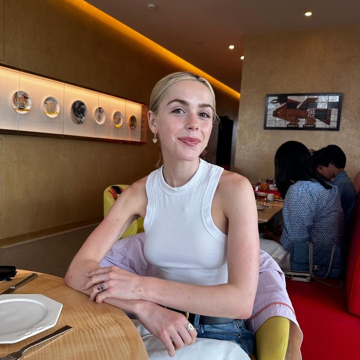 a woman sitting at a table in a restaurant with her arms crossed and legs crossed