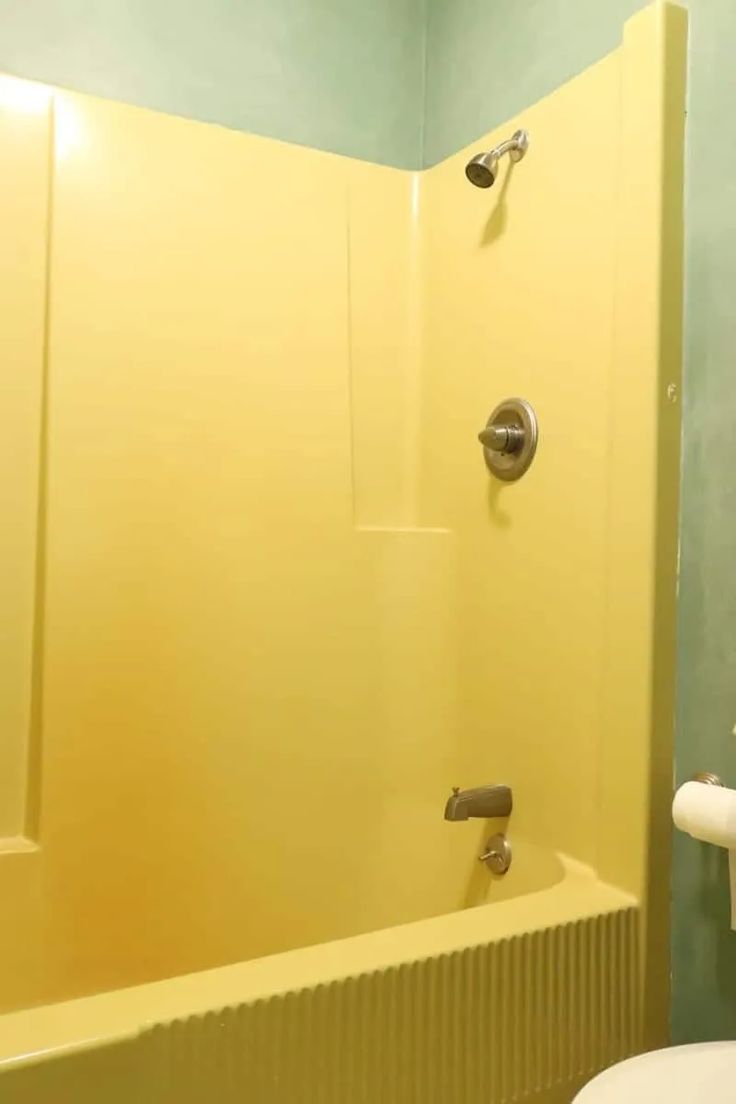 a bathroom with yellow walls and a white toilet sitting next to a bathtub in the corner