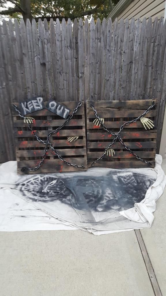 two wooden pallets that have been chained to the side of a fence with words written on them