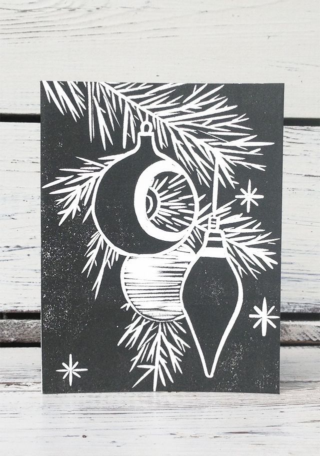 a black and white christmas card with an ornament hanging from a pine tree