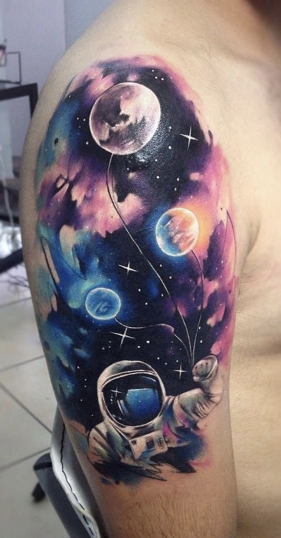 an astronaut tattoo on the right arm and shoulder, with planets in the sky behind it