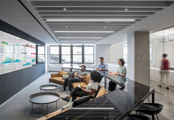 people are sitting at tables in an office with black and white decor on the walls