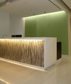 an empty reception area with white walls and green accenting the wall is lit by recessed lighting